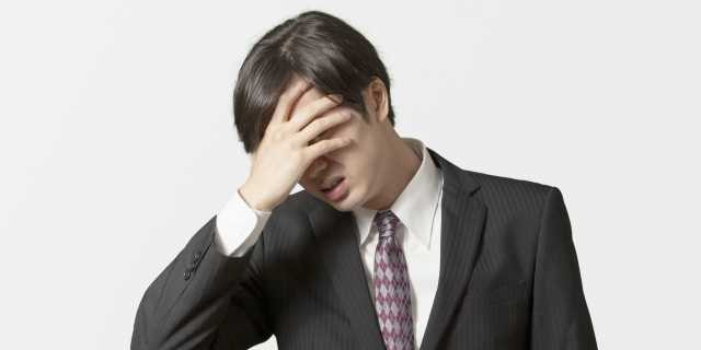 頭を抱えるスーツを着た男性